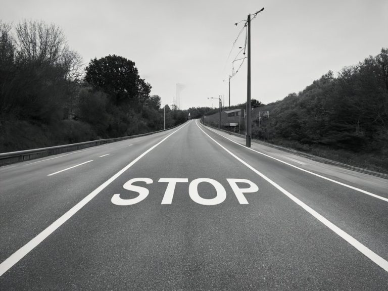 Blick auf eine leere Straße mit „STOP“ in großen Buchstaben darauf.